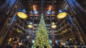 A very grand Christmas tree decorated with white lights and wilderness-inspired ornaments is displayed in the lobby of Disney’s Wilderness Lodge. Matching garlands hang from the upper floor balconies as guests explore the resort.