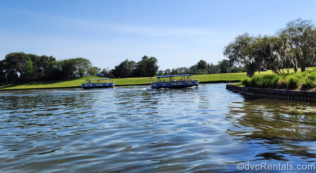 Two yellow and blue boats sail along the path from Disney’s Old Key West and Saratoga Springs Resort & Spa to Disney Springs under a blue sky.