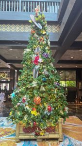 A green Christmas tree decorated with tiki and island-inspired ornaments is seen in the main lobby of Disney’s Polynesian Villas & Bungalows.