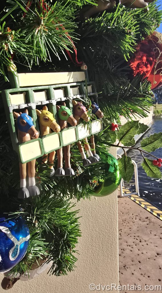 A garland decorated with an ornament showing several race horses lined up at a starting gate is hung outdoors at Disney’s Saratoga Springs Resort & Spa.
