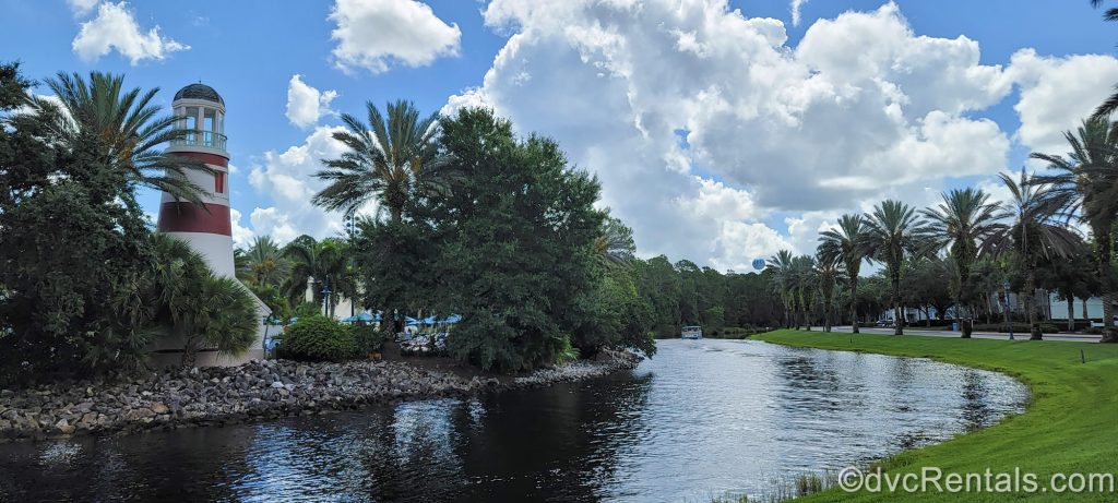 One of Disney’s water taxis is seen in the distance as it heads past the buildings and landscaping of Disney’s Old Key West Resort towards Disney Springs on a sunny day.