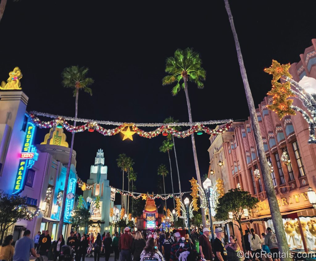 Silver tinsel garlands with sparkling stars and colorful ornaments are hung above the crowds entering Disney Jollywood Nights down Hollywood Boulevard in Disney’s Hollywood Studios Theme Park.