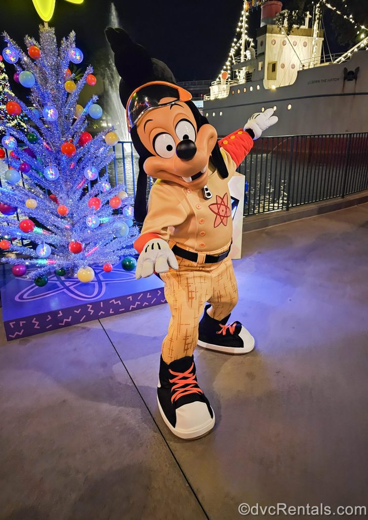 Max Goof in his Powerline outfit poses in front of a colorful Christmas tree at Disney’s Hollywood Studios during Disney Jollywood Nights.