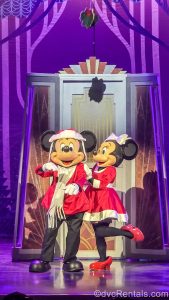 Mickey and Minnie Mouse pose together in red and white holiday outfits during a performance of Disney Holidays in Hollywood during Disney Jollywood Nights.