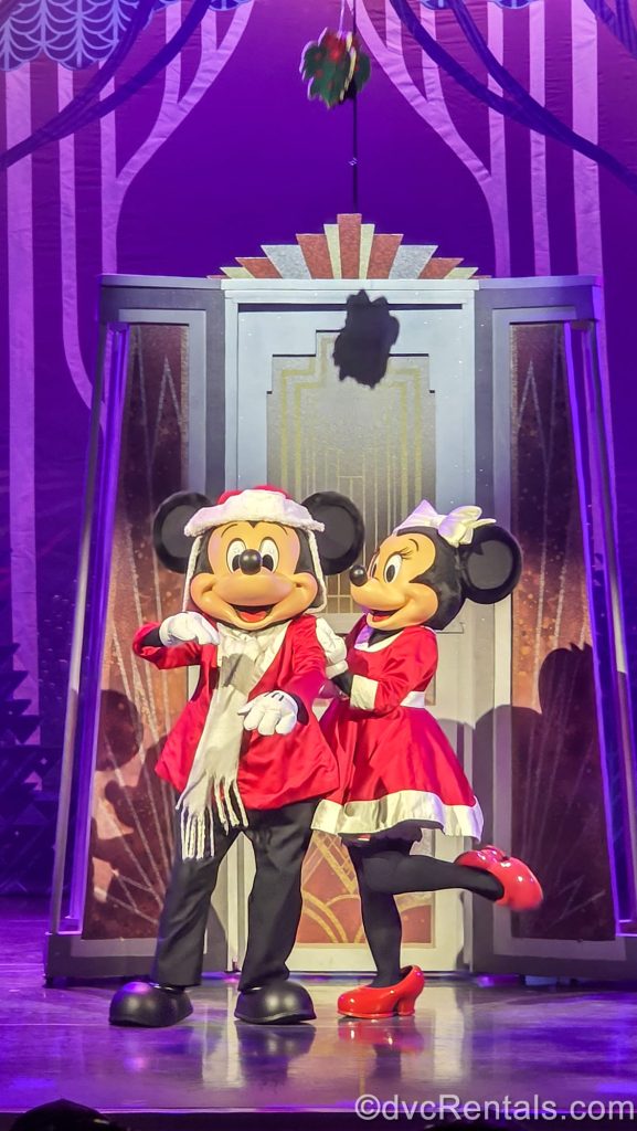 Mickey and Minnie Mouse pose together in red and white holiday outfits during a performance of Disney Holidays in Hollywood during Disney Jollywood Nights.