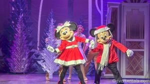 Minnie Mouse, Mickey Mouse, and other performers dance in red and white seasonal costumes during the Disney Holidays in Hollywood show.