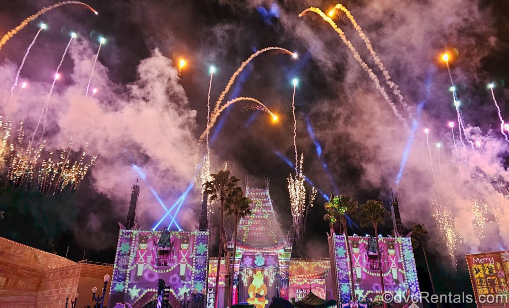 The Chinese Theatre at Disney’s Hollywood Studios is lit up with colorful Christmas projections as fireworks and lasers sparkle in the sky during Jingle Bell, Jingle BAM!