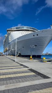 The white exterior of Royal Caribbean’s Wonder of the Seas cruise ship is seen docked in port under a sunny blue sky.