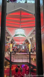 The Royal Promenade on Wonder of the Seas is seen as guests walk up and down the red and white lit space full of shops and dining locations.