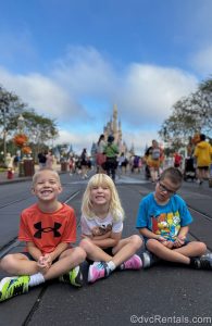 The children in Guest Blogger ErinAdvocates’ family sit on Main Street U.S.A. under a blue sky and smile for a photo in front of Cinderella Castle at the Magic Kingdom.