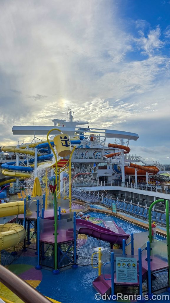 The colorful waterplay area and waterslides onboard the Wonder of the Seas cruise ship are seen under a hazy blue sky.
