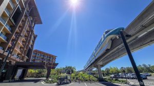 The monorail passes by the exterior of the Island Tower at Disney’s Polynesian Villas & Bungalows under a sunny, blue sky.