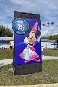 Minnie Mouse in a pink princess costume is seen on mile-marker and time signage stationed along the race route during a runDisney race event.