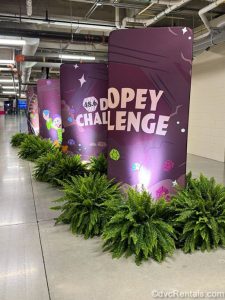 Purple stanchion signs decorated with multi-colored jewels and a drawing of Dopey are displayed, reading “48.6 Dopey Challenge” in light pink lettering.