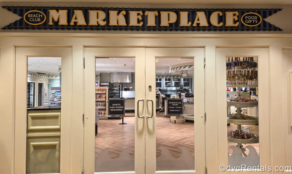 The white entry doors to the Beach Club Marketplace are seen at Disney’s Beach Club Villas. Food items and candy are seen through the glass windows of the doors.