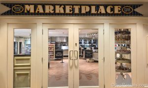The white entry doors to the Beach Club Marketplace are seen at Disney’s Beach Club Villas. Food items and candy are seen through the glass windows of the doors.