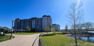 Disney’s Riviera Resort grounds are seen from a distance under a bright blue sky from a walking pathway near the resort’s Skyliner station.