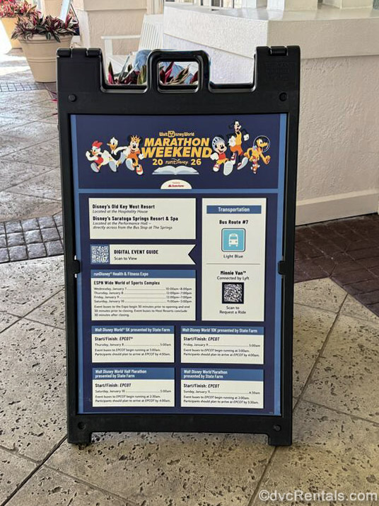 A blue and black sign displaying transportation information and event times for the 2026 Walt Disney World Marathon weekend is displayed at Disney’s Old Key West Resort.