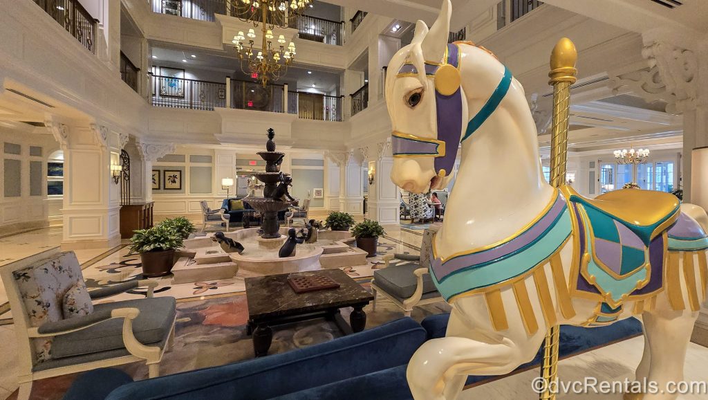 A colorful carousel horse and penguin fountain inspired by the film Mary Poppins decorate the lobby seating area at the Villas at Disney’s Grand Floridian Resort & Spa.