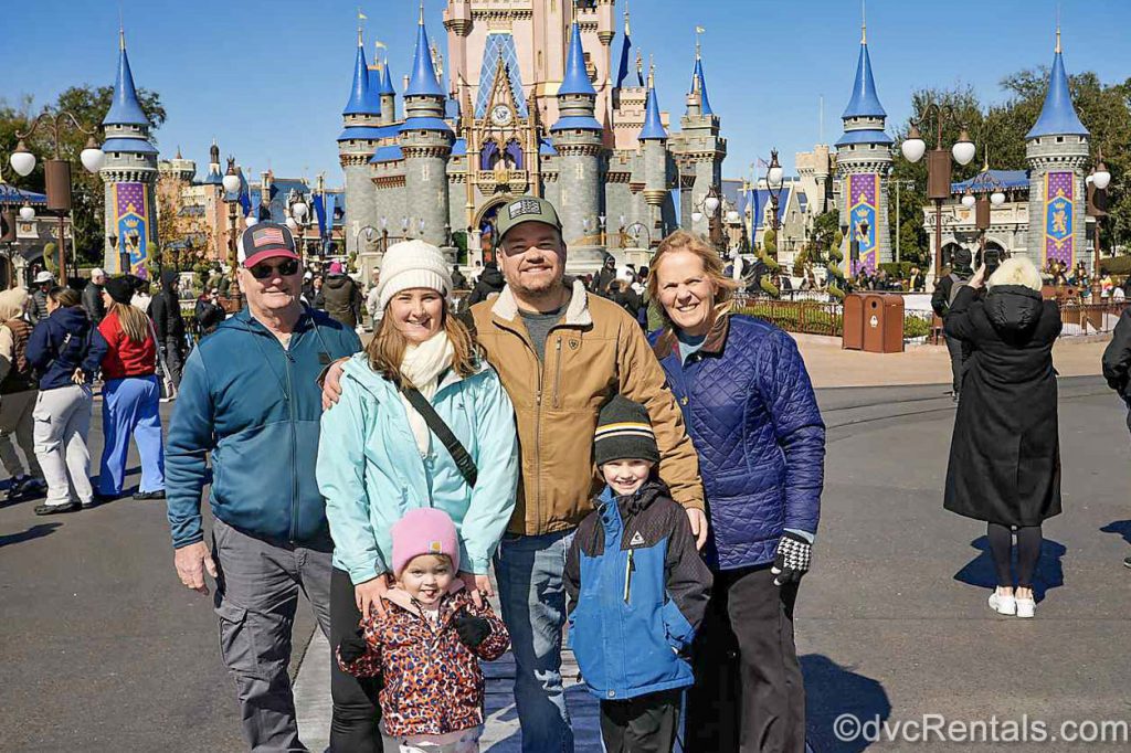 Guest blogger Christie Hecht and her family pose with smiles in front of Cinderella Castle at the Magic Kingdom at Walt Disney World under a blue sky.