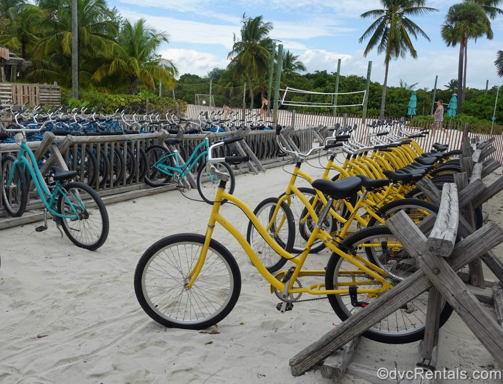 Yellow and teal bicycles are seen parked in the sand ready for rental at Disney Castaway Cay.