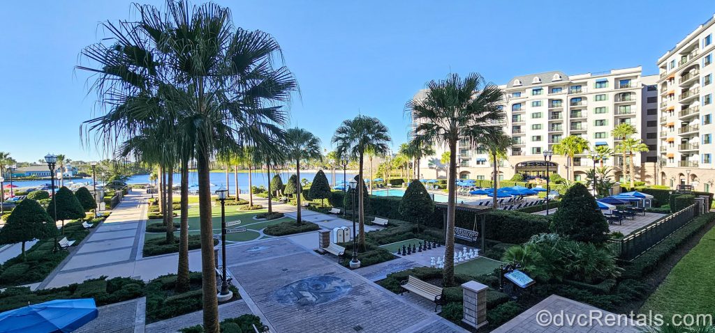 The exterior landscaping, walkways, and quiet pool at Disney’s Riviera Resort are seen under a blue sky.