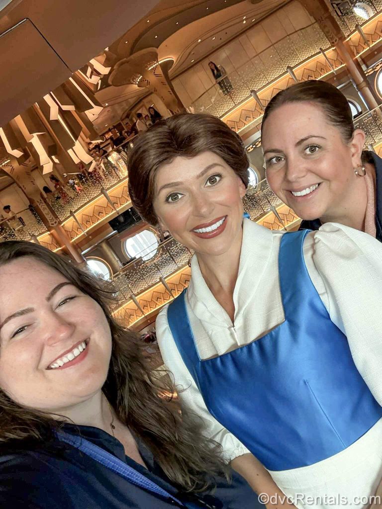 David’s Vacation Club Rentals team members Elyse and Stacy pose with Belle in the ship’s Grand Hall.