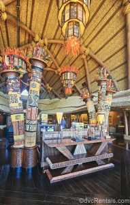African art and artifacts are displayed in the lobby of Disney’s Animal Kingdom Villas Kidani Village. The lobby is decorated in warm oranges, reds, yellows, and dark woods.