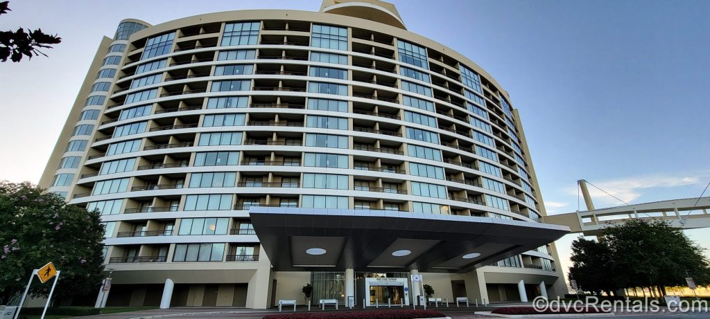 The curved exterior of Bay Lake Tower at Disney’s Contemporary Resort is seen under a blue sky during golden hour.