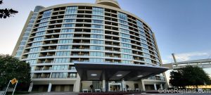 The curved exterior of Bay Lake Tower at Disney’s Contemporary Resort is seen under a blue sky during golden hour.