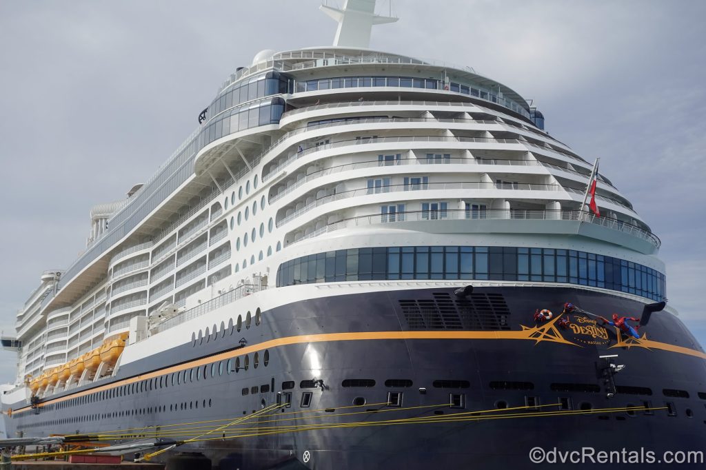 The white and blue exterior of the Disney Destiny is seen docked under a hazy sky.