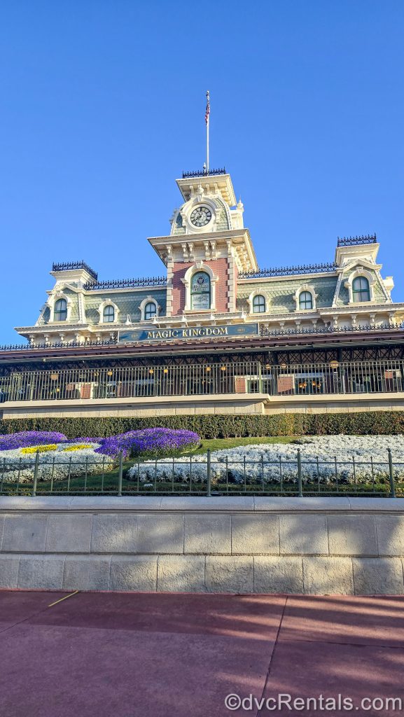 The Train Station stands over the entry way to the Magic Kingdom at Walt Disney World under a sunny, blue sky.
