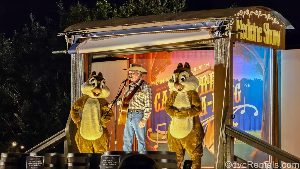 Characters Chip ‘n’ Dale and their cowboy host lead a Campfire Sing-A-Long under the stars on a wooden wagon-themed stage.