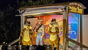 Characters Chip ‘n’ Dale and their cowboy host lead a Campfire Sing-A-Long under the stars on a wooden wagon-themed stage.
