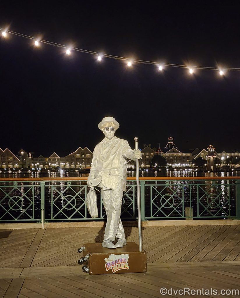 A performer dressed in a silver suit designed to look like a statue entertains guests under a night sky at Disney’s BoardWalk Villas.