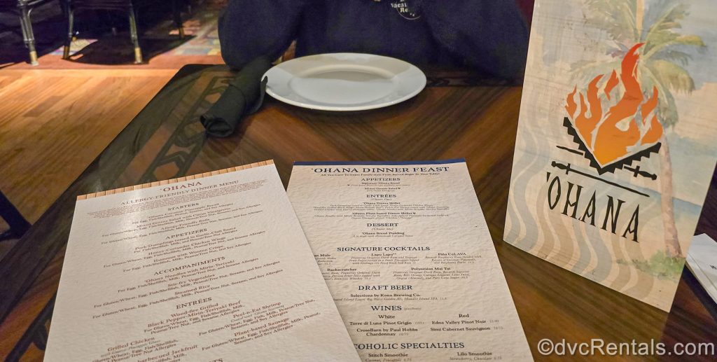 ‘Ohana dinner and allergy menus are seen on a dark wood table inside the restaurant at Disney’s Polynesian Villas & Bunaglows.
