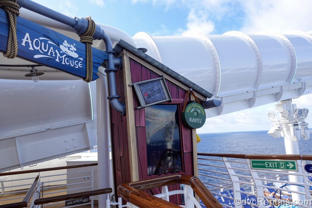 The entrance to the AquaMouse water coaster and the white tubing of the slide are seen under a blue sky on the upper decks of the Disney Destiny.