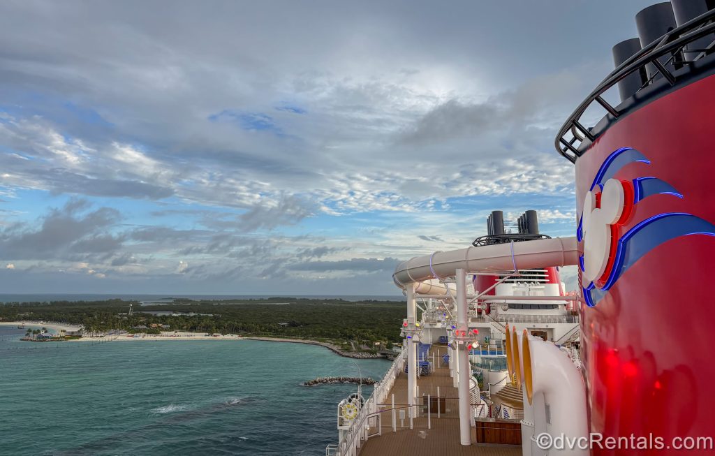 The side of the top decks of the Disney Destiny are seen under a blue morning sky as the ship arrives at Disney Castaway Cay in the Bahamas.