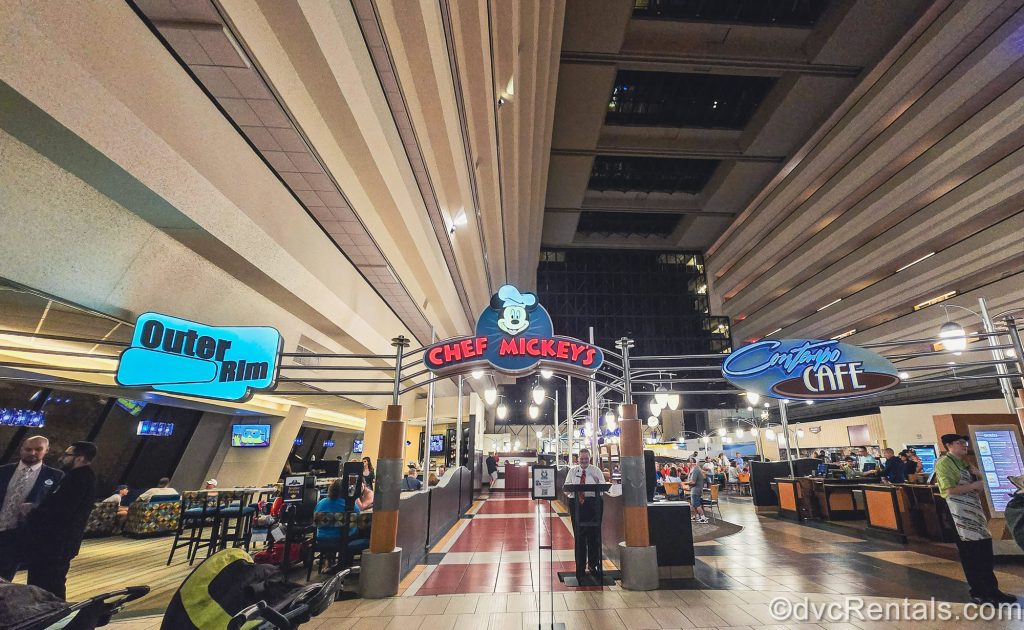 Colorful signs for restaurants at Disney’s Contemporary Resort are seen as guests sit enjoying their meals, including Chef Mickey’s, Outer Rim, and Contempo Café.
