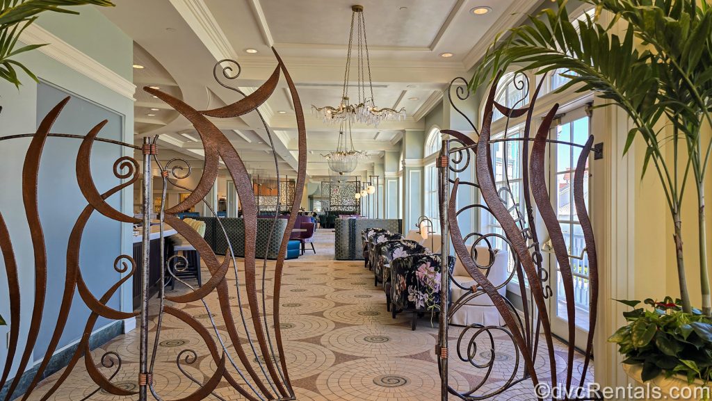 The ornate brown entry way to Citricos at Disney’s Grand Floridian Resort & Spa is seen. Elegant floral chairs and barstools can be seen in the lounge area, leading to the blue and purple Mary Poppins Returns-themed dining room.