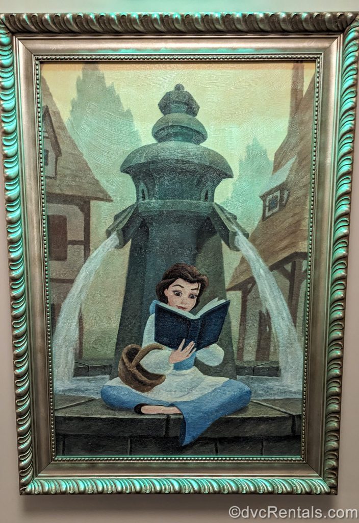 A framed painting depicting Belle reading a book in front of a fountain is seen at Disney’s Riviera Resort.