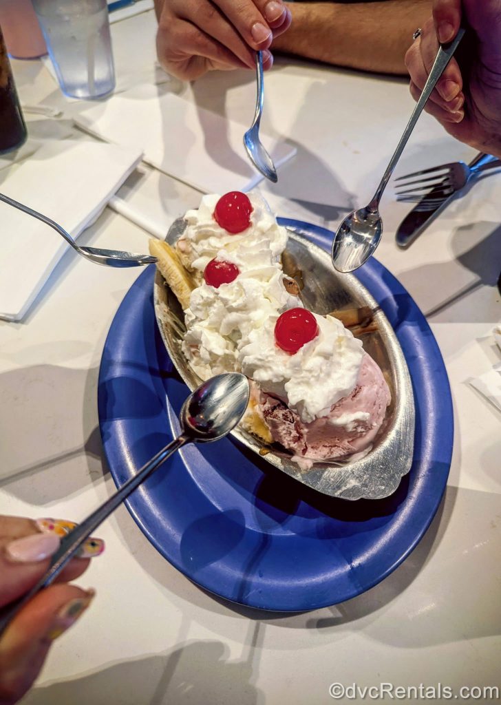 David’s Vacation Club Rentals team members aim silver spoons at an ice cream treat at Beaches & Cream Soda Shop at Disney’s Beach Club Villas.