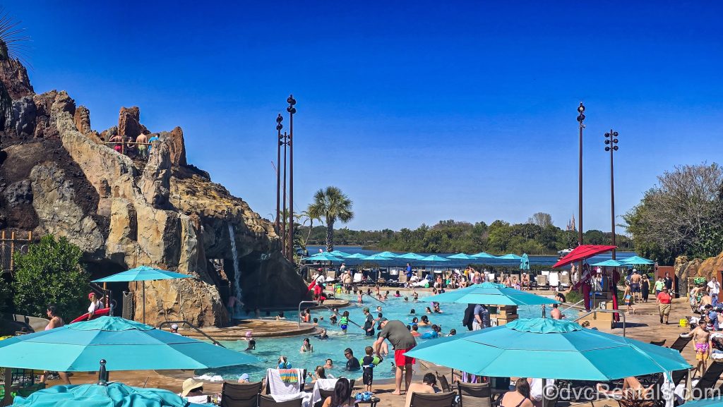 Resort guests enjoy the volcano-inspired Lava Pool at Disney’s Polynesian Villas & Bungalows under a bright blue sky.