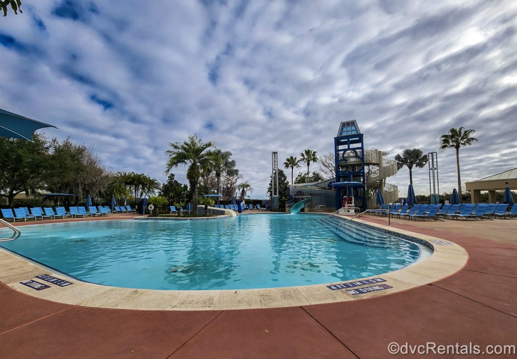 The Bay Cove Pool at Bay Lake Tower at Disney’s Contemporary Resort is seen under a blue sky filled with fluffy white clouds.