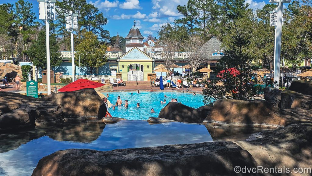 The rocky formation around the High Rock Spring feature pool looks down over guests enjoying the pool under a blue sky.