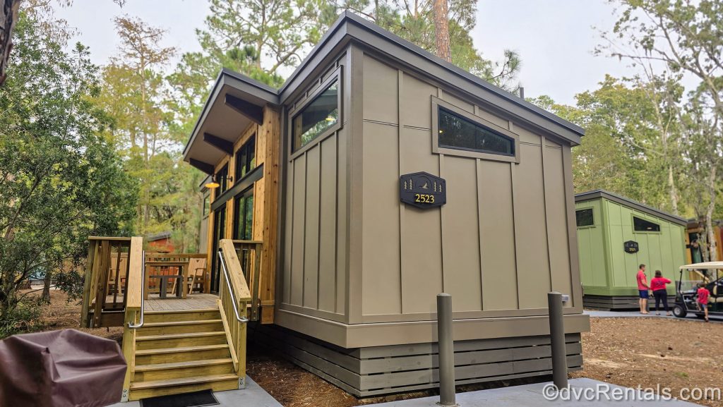 The brown and green exteriors of some One Bedroom Cabins are seen within the wooded grounds of Disney’s Fort Wilderness Resort.