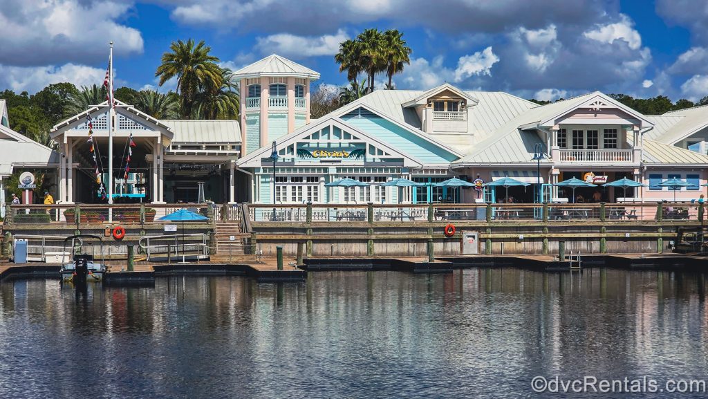 The amenities of Hospitality House including Olivia’s Café and the water taxi launch are seen under a sunny sky at Disney’s Old Key West Resort.