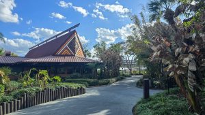 The dark brown exterior of a Longhouse and grounds landscaping at Disney’s Polynesian Villas & Bungalows. The monorail can be seen going by in the distance.
