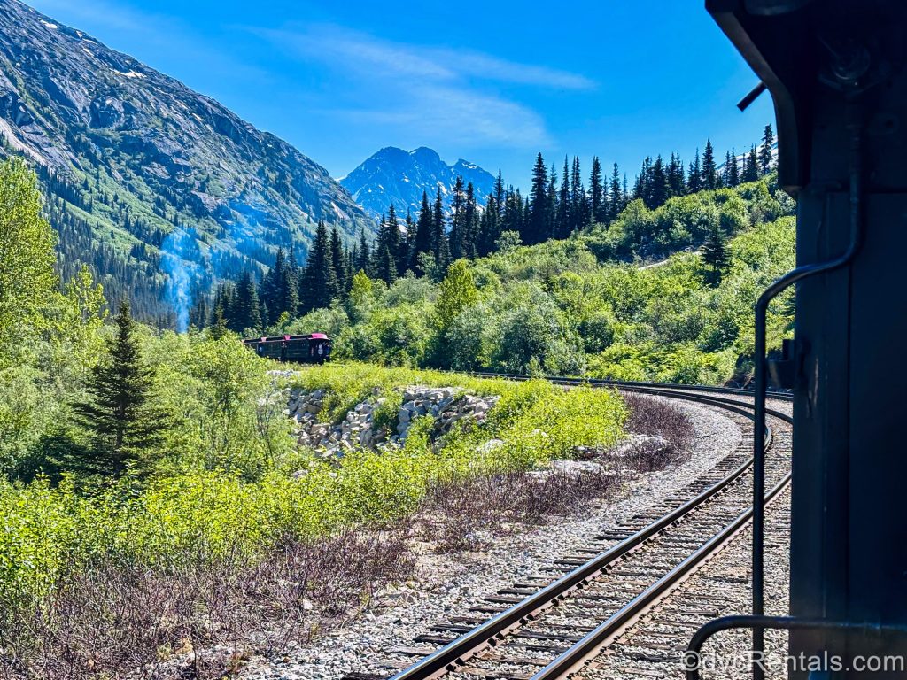 Trains pass each other along the tracks on the White Pass Yukon Route in Skagway, Alaska as they take visitors through the beautiful mountainous landscape and trails from the Klondike age.