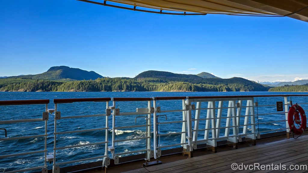 Forests and mountains are seen in the distance from the outdoor decks of the Disney Magic under a blue sky as it sails back to Vancouver from Alaska.